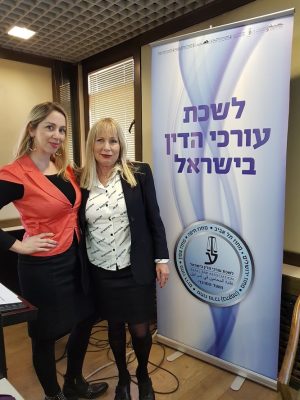 שתי נשים עומדות ליד שלט לשכת עורכי הדין בישראל באירוע